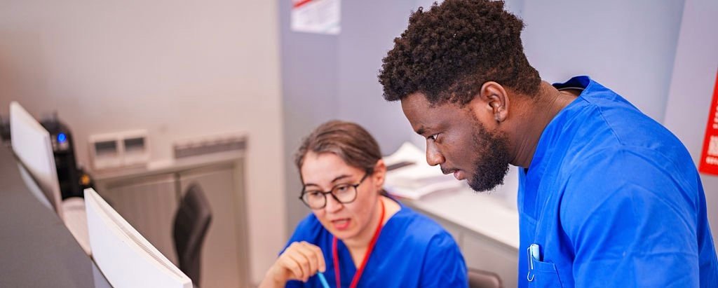 2 2 A Black male and a White female healthcare professional work together in a clinical setting, sharing ideas and collaborating on patient care. The scene highlights teamwork, diversity, and medical expertise in modern healthcare.
